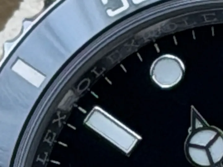Makroaufnahme der Rehaut einer Rolex Submariner Date mit der umlaufenden Gravur „ROLEX“ zwischen Zifferblatt und Glas