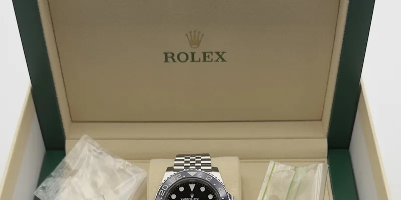 Geöffnete grüne Rolex-Box mit Uhr und Zubehörbeuteln