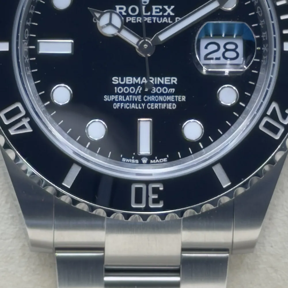 Detailaufnahme einer Rolex Submariner: unteres Zifferblatt, Rehaut bei 6 Uhr, Lünette und Gehäuse